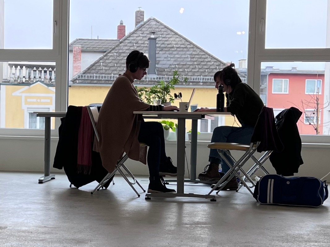 Zwei Menschen in Community-Lofts beim Arbeiten vor Glasfenster